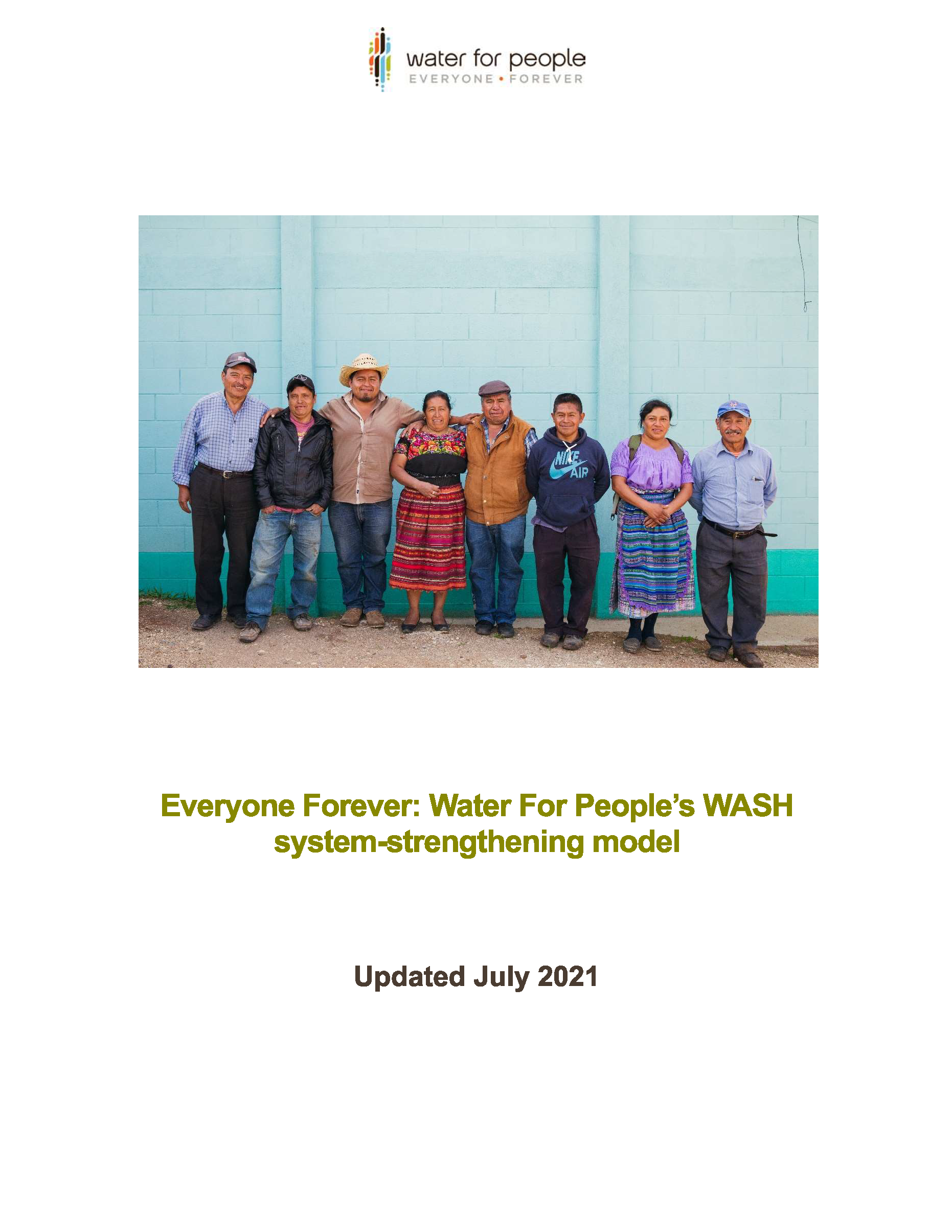 Briefing Note Cover Page. There is a large photo of eight people standing in a line. There are two women and six men. They are outside on a dirt path in front of a large blue concrete brick wall.