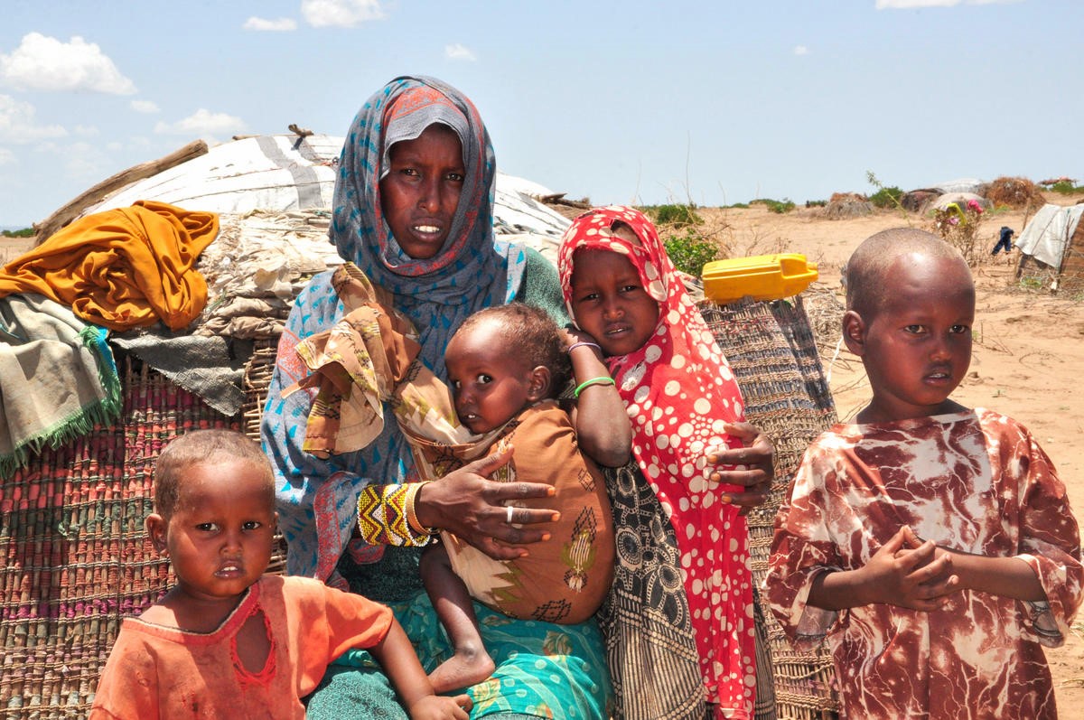 A mother standing in front of a temporary settlement in Ethiopia surrounded by four of her children.