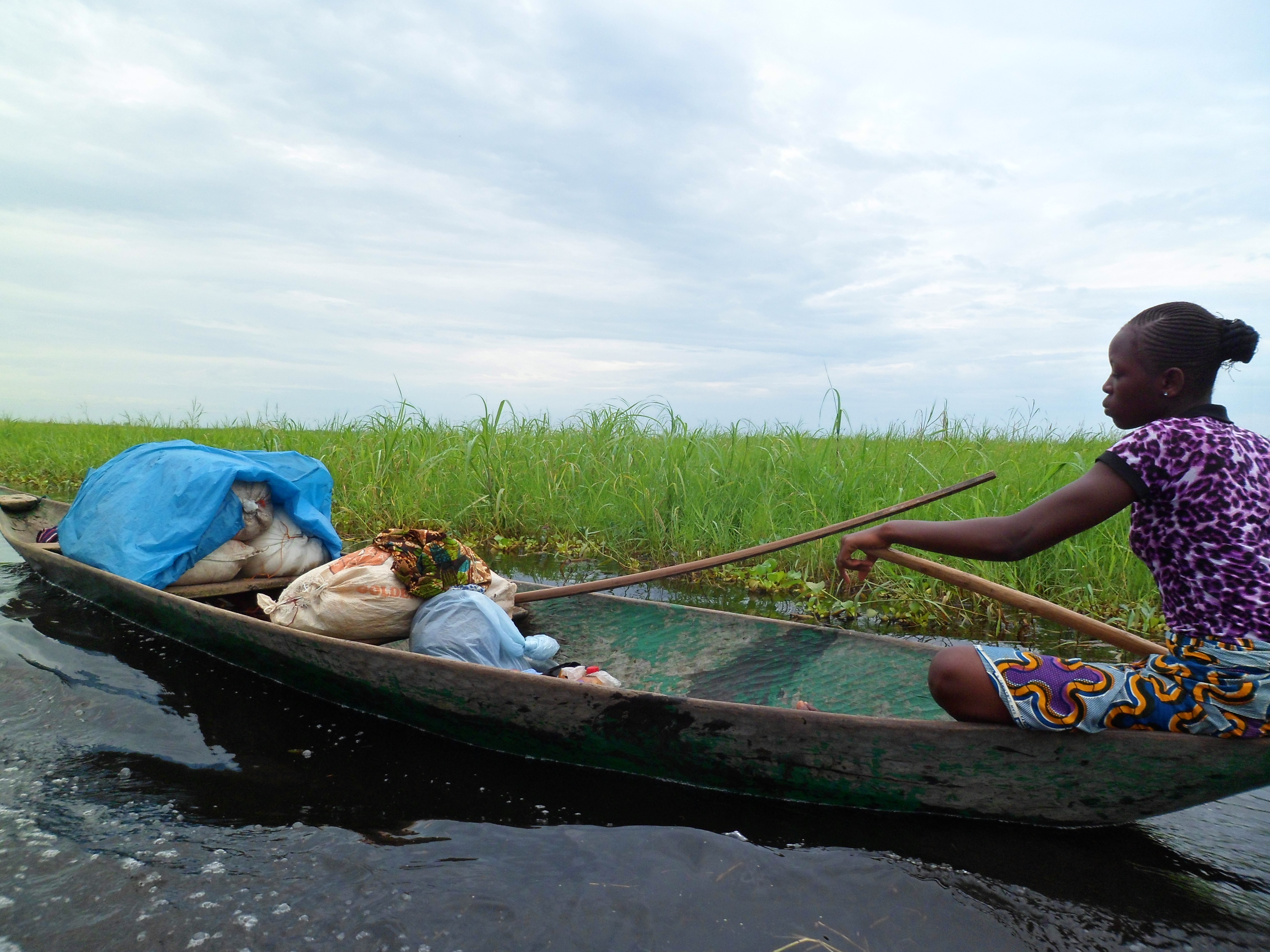 A woman sits in a boat, working in a fishery in Benin.