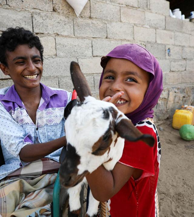 children smiling while holding a goat