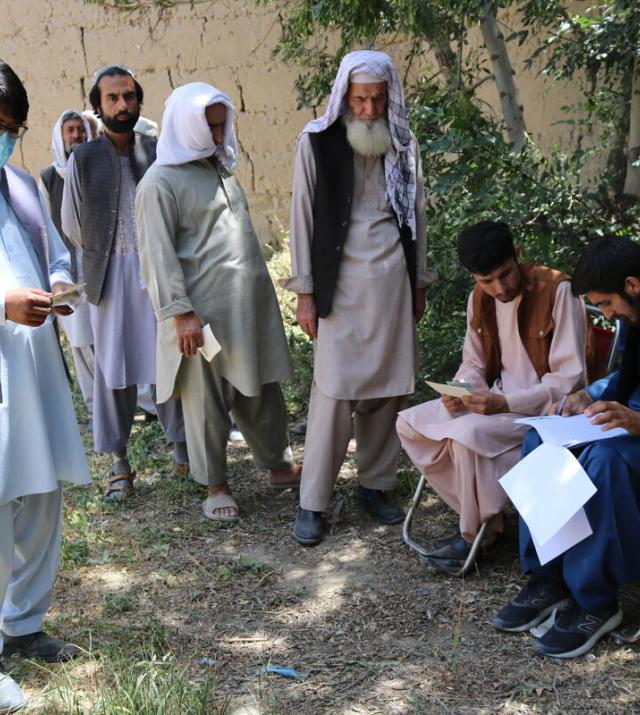 Four men line up to receive cash voucher assistance in Afghanistan