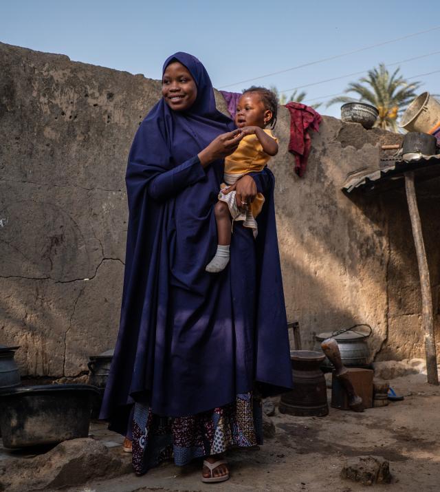 Amina holds her younger sibling Saratou, who has recently recovered from pneumonia, outside their home in Jigawa State, Nigeria