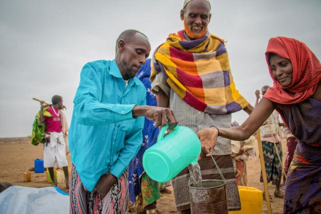 man giving water to a woman