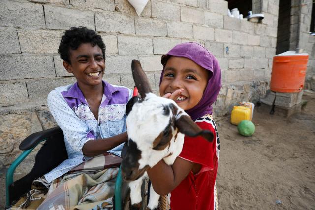 children smiling while holding a goat