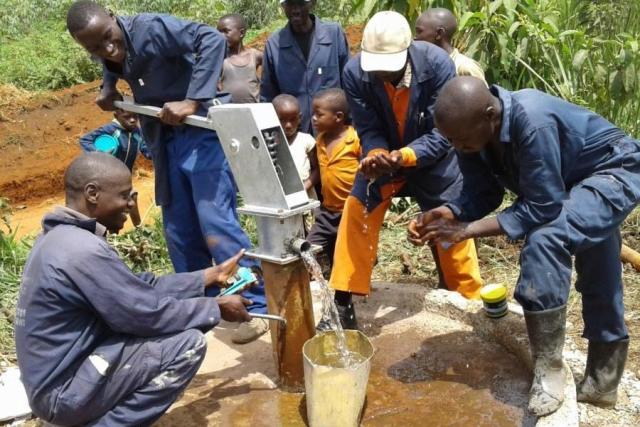 A group of men and children gather around a well.