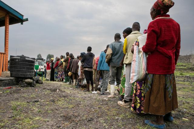 A group of people line up outside a distribution center in Eastern DRC